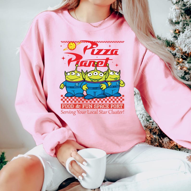 a woman in a pink sweatshirt is holding a coffee mug