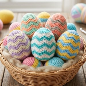 Op de afbeelding: Een rieten mand gevuld met kleurrijke, gehaakte paaseieren. De eieren hebben verschillende patronen en kleuren, waaronder blauw, geel, roze en oranje. De mand staat op een rustiek houten oppervlak, met een raam op de achtergrond.