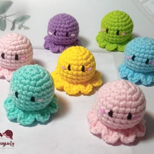 May include: A set of eight crocheted octopus plushies in various colors, including pink, purple, yellow, green, and blue. Each octopus has a cute face with black eyes and pink cheeks.
