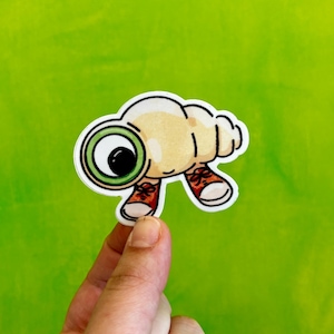 May include: A cartoon snail with a large green eye and red shoes. The snail is wearing a shell and has a friendly expression.