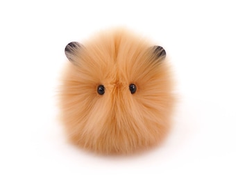 May include: A small, fluffy, orange-brown plush toy with black eyes and ears. The toy is shaped like a ball and has a soft, fuzzy texture.