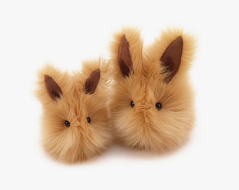 May include: Two fluffy brown plush bunnies with black eyes and brown ears. The larger bunny is on the right and the smaller bunny is on the left.