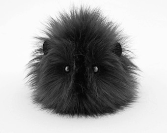 May include: A black plush toy shaped like a round, furry creature with large black eyes. The toy has a fluffy, soft texture.