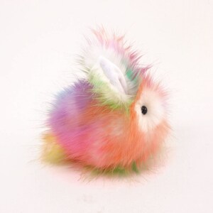 May include: A fluffy rainbow-coloured plush bunny toy with white ears and black eyes.