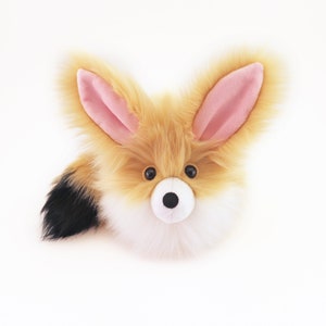 May include: A plush fox toy with a fluffy tail, orange and white fur, and pink ears. The toy has black eyes and a black nose.