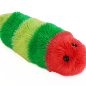 May include: A plush toy shaped like a worm with green, lime green, and red stripes. The toy has black eyes and a fuzzy texture.