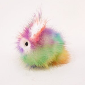 May include: A fluffy rainbow-coloured plush bunny toy with a white ear and a black eye.