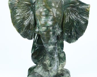May include: A green agate elephant sculpture with intricate details. The elephant is carved in a sitting position with its trunk raised.