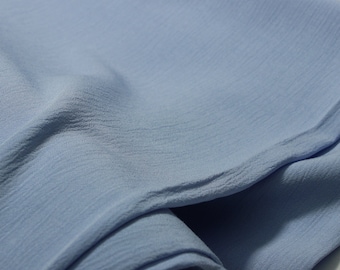 May include: A light blue fabric with a textured surface. The fabric is folded and rolled up.