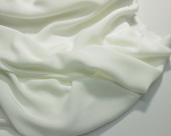 May include: White fabric with a subtle ribbed texture. The fabric is draped and folded, creating soft folds and curves.