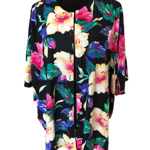 May include: A black button-up shirt with a large floral print in shades of pink, yellow, green, and blue.