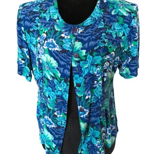 May include: A blue and green floral print button-up shirt with short sleeves.
