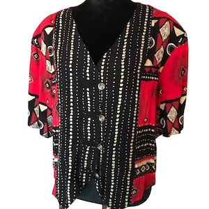 May include: A red and black patterned button-up blouse with short sleeves. The blouse has a V-neck and a geometric pattern.
