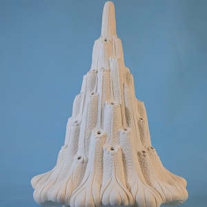 May include: A white ceramic tree-shaped sculpture with a textured surface and a star-shaped base. The sculpture has a series of openings and a pointed top. The background is a solid light blue.