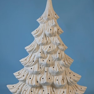 May include: A ceramic Christmas tree in off-white. The tree has a textured, layered design with small holes for lights. The base features a holly leaf design. The tree is a festive decoration for the holiday season.
