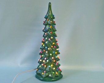 May include: A green ceramic Christmas tree with colorful lights. The tree is lit and has a cord for plugging in.