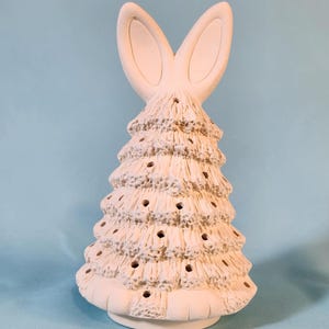 May include: White ceramic Christmas tree with bunny ears on top. The tree has a textured surface and holes for lights.