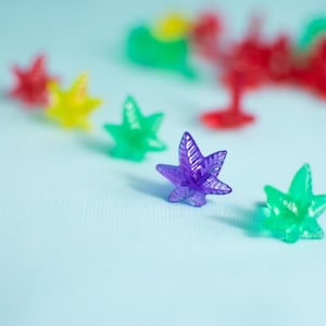 May include: A collection of colorful star-shaped ornaments in red, yellow, green, and purple. The ornaments are made of plastic and have a shiny finish.