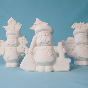 May include: Three white ceramic figurines of people with different accessories. The figurine on the left is holding a cup and a small bird. The figurine in the middle is wearing a chef's hat and holding a rolling pin. The figurine on the right is wearing a bat hat and holding a bottle.