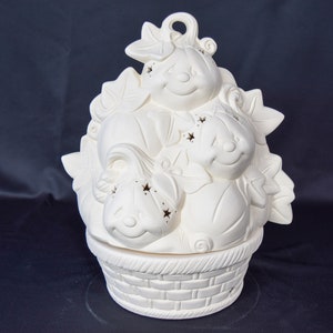 May include: White ceramic pumpkin candle holder with three pumpkins in a basket. The pumpkins have cut-out stars and smiling faces.