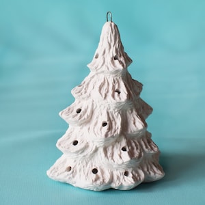 May include: White ceramic Christmas tree ornament with a textured surface and holes for lights. The ornament has a wire loop for hanging.