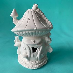 Puede incluir: Casa de cerámica blanca en forma de hongo con una pequeña puerta y una oruga en el techo. La casa tiene un diseño caprichoso con detalles como una abeja y una mariquita.