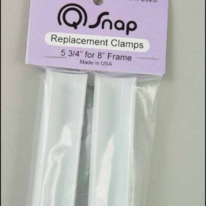 May include: Two white plastic replacement clamps for a 5 3/4 inch frame. The clamps are packaged in a clear plastic bag with a purple label that reads "Genuine Q-Snap Replacement Clamps 5 3/4" for 8" Frame Made in USA" and "Item 2926".