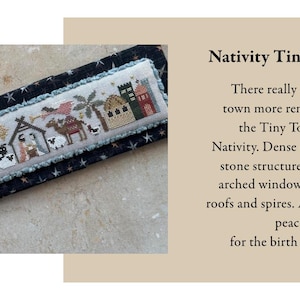 May include: A cross-stitch embroidery featuring a Nativity scene with buildings, palm trees, and animals. The text "Nativity Tiny Town" is displayed. The embroidery is set on a dark blue fabric with white stars.