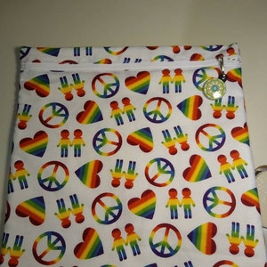 May include: White zippered pouch with a repeating pattern of rainbow hearts, peace signs, and figures holding hands. A small charm hangs from the zipper pull. The pouch is likely made of fabric and is designed for carrying items.