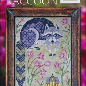 May include: A cross-stitch pattern featuring a raccoon in a woodland setting. The raccoon is sitting on a log with its tail curled around it. The background is a green and brown woodland scene with pink flowers.