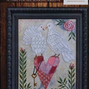 May include: Cross stitch pattern featuring two white doves perched on a pink heart with a key. The doves are facing each other and appear to be kissing. The pattern is titled "Love is in the Air" and is part of the "A Time for All Seasons Series #2" collection.
