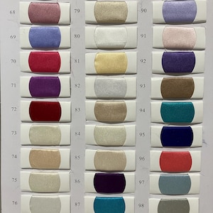 May include: A color chart featuring a variety of fabric swatches. The swatches are rectangular, with a central colored fabric section and white borders. Colors range from greens and reds to blues and golds, with numbers from 67 to 99.
