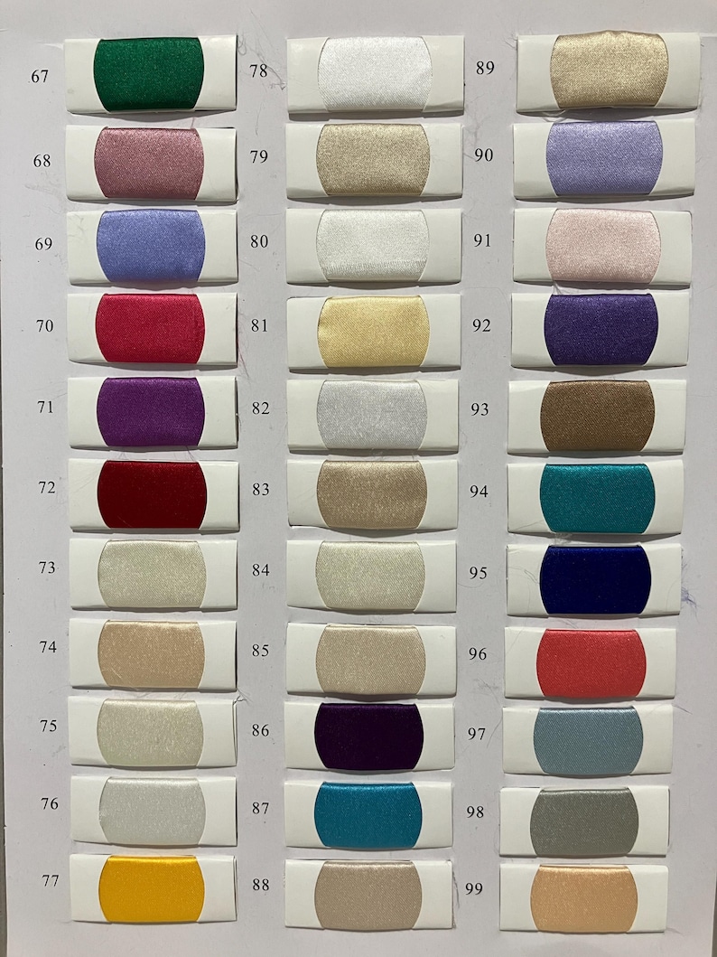 May include: A color chart featuring a variety of fabric swatches. The swatches are rectangular, with a central colored fabric section and white borders. Colors range from greens and reds to blues and golds, with numbers from 67 to 99.