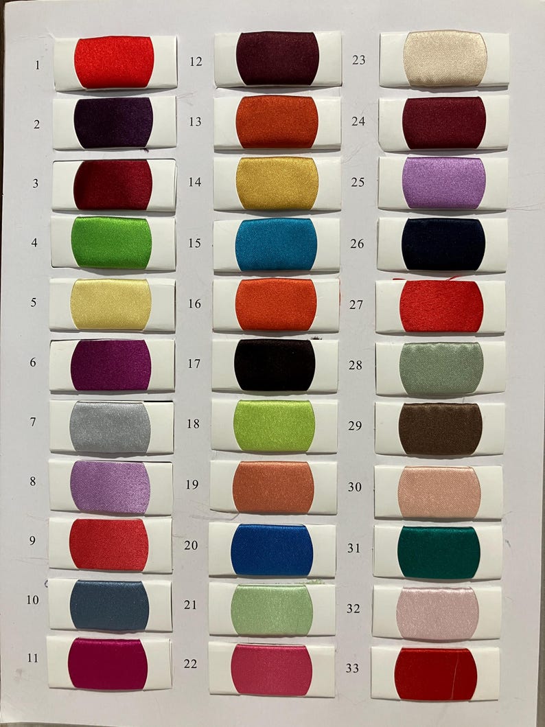 May include: A color swatch chart featuring 33 fabric samples in various colors. The samples are rectangular with rounded ends, each mounted on a white card. Colors include red, purple, green, yellow, and blue.