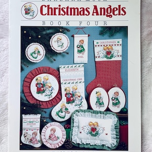 May include: A book cover titled "Christmas Angels" by Barbara Mock, featuring cross-stitch designs. The cover displays various Christmas-themed cross-stitch projects, including angel motifs, stockings, and ornaments. The book is labeled "Book Four" and includes the Dimensions logo.