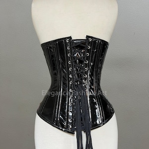 Pu&ograve; includere: Corsetto in pelle verniciata nera con lacci sul retro e una lunga cravatta fluida. Il corsetto ha una struttura a stecche e un fondo a punta.