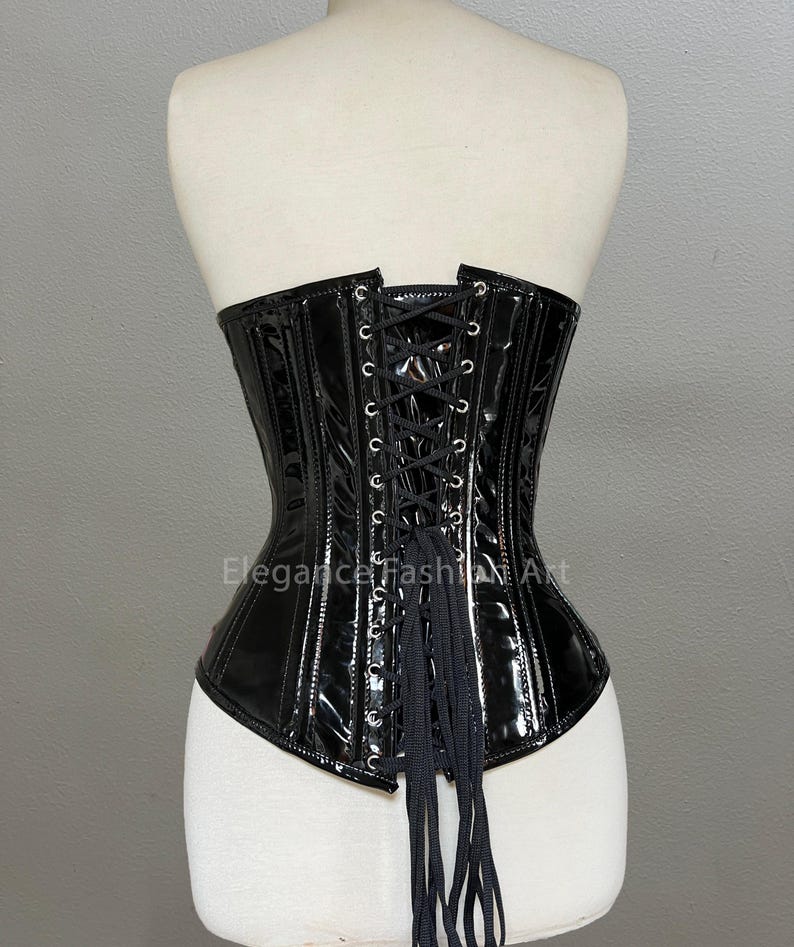 Pu&ograve; includere: Corsetto in pelle verniciata nera con lacci sul retro e una lunga cravatta fluida. Il corsetto ha una struttura a stecche e un fondo a punta.