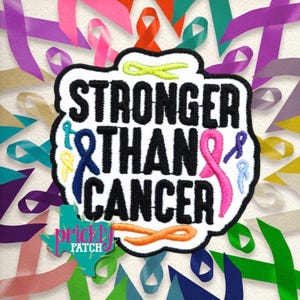May include: An embroidered patch featuring the black text STRONGER THAN CANCER. The design includes a lime green ribbon at the top, a blue ribbon on the left, a pink ribbon on the right, and an orange ribbon at the bottom, all on a white background.
