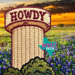 May include: An embroidered patch featuring a tall, tan, cylindrical cactus with vertical stitching and a dark red border. The word HOWDY is stitched in dark red letters at the top. Dark green, rounded, textured bushes are at the base of the cactus.
