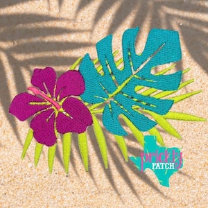May include: An embroidered patch featuring a vibrant purple hibiscus flower, a teal monstera leaf, and light green palm fronds. The design includes a small teal Texas-shaped logo with the text Prickly Patch in white lettering.