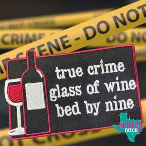 May include: Black rectangular patch with red trim featuring a wine bottle and glass design. Text reads "true crime glass of wine bed by nine." Yellow crime scene tape is in the background.