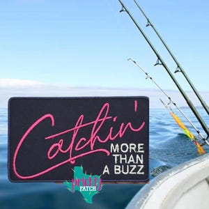 May include: A navy blue patch with the words "Catchin' More Than A Buzz" in pink and white script. The patch also features a teal Texas-shaped logo. Fishing rods are visible in the background against a blue sky and water.