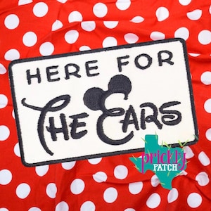 May include: Embroidered patch with the text "HERE FOR THE EARS" in black on a white rectangular background. The design includes a silhouette of Mickey Mouse ears. The patch is set against a red fabric with white polka dots.