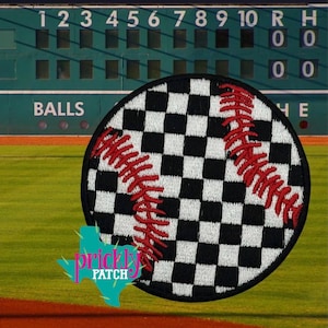 May include: A round baseball patch with a black and white checkered pattern and red stitching. The patch is set against a baseball field background with a green scoreboard and the word "BALLS" visible.
