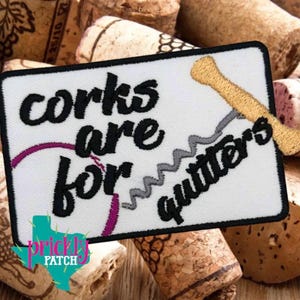 May include: Embroidered patch with the text "corks are for quitters" in black script. The patch features a wine bottle opener and a purple wine stain design. The background is white with a black border.
