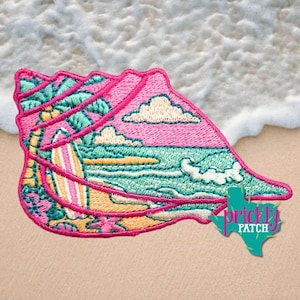 May include: An embroidered patch shaped like a seashell featuring a beach scene with a palm tree, a surfboard, and ocean waves. The design uses vibrant pink, teal, yellow, and white thread. The text Prickly Patch is visible in a teal shape.