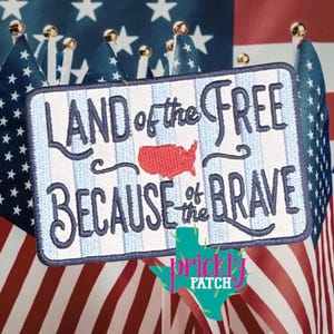 May include: Embroidered patch with the text "LAND of the FREE BECAUSE of the BRAVE" and a red outline of the United States. The patch has a blue and white striped background and is surrounded by American flags.