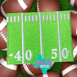 May include: A square embroidered patch featuring a bright green football field design with white yard lines, hash marks, and the numbers 40 and 50. The patch has a clean, stitched border and is displayed against a background of brown footballs.