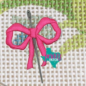 Puede incluir: Una aguja con un eje gris está enhebrada a través de un lazo rosa brillante, bordado sobre un lienzo de malla blanca. El fondo presenta un diseño floral verde y azul. El logotipo de Prickly Patch está en la esquina inferior derecha.