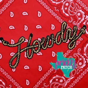 May include: A red bandana with a white paisley pattern and the word "Howdy" embroidered in a rope-like font. A turquoise and pink Texas-shaped logo is in the lower right corner.